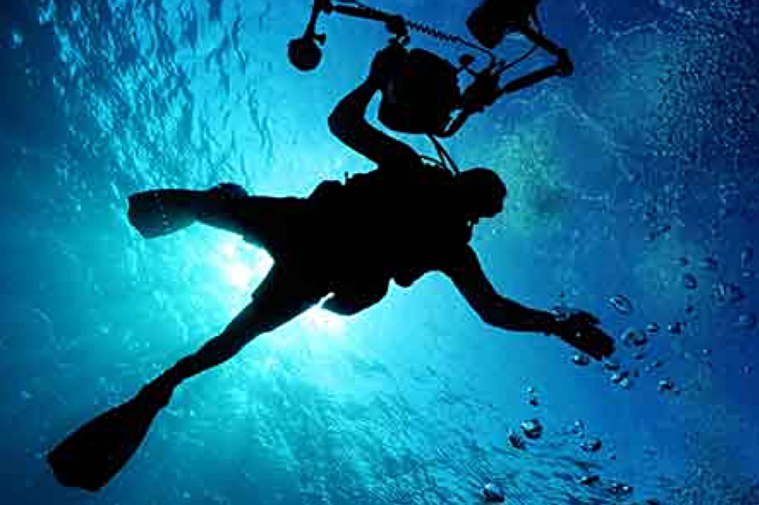 Scuba diver captured in silhouette with sunlight and bubbles