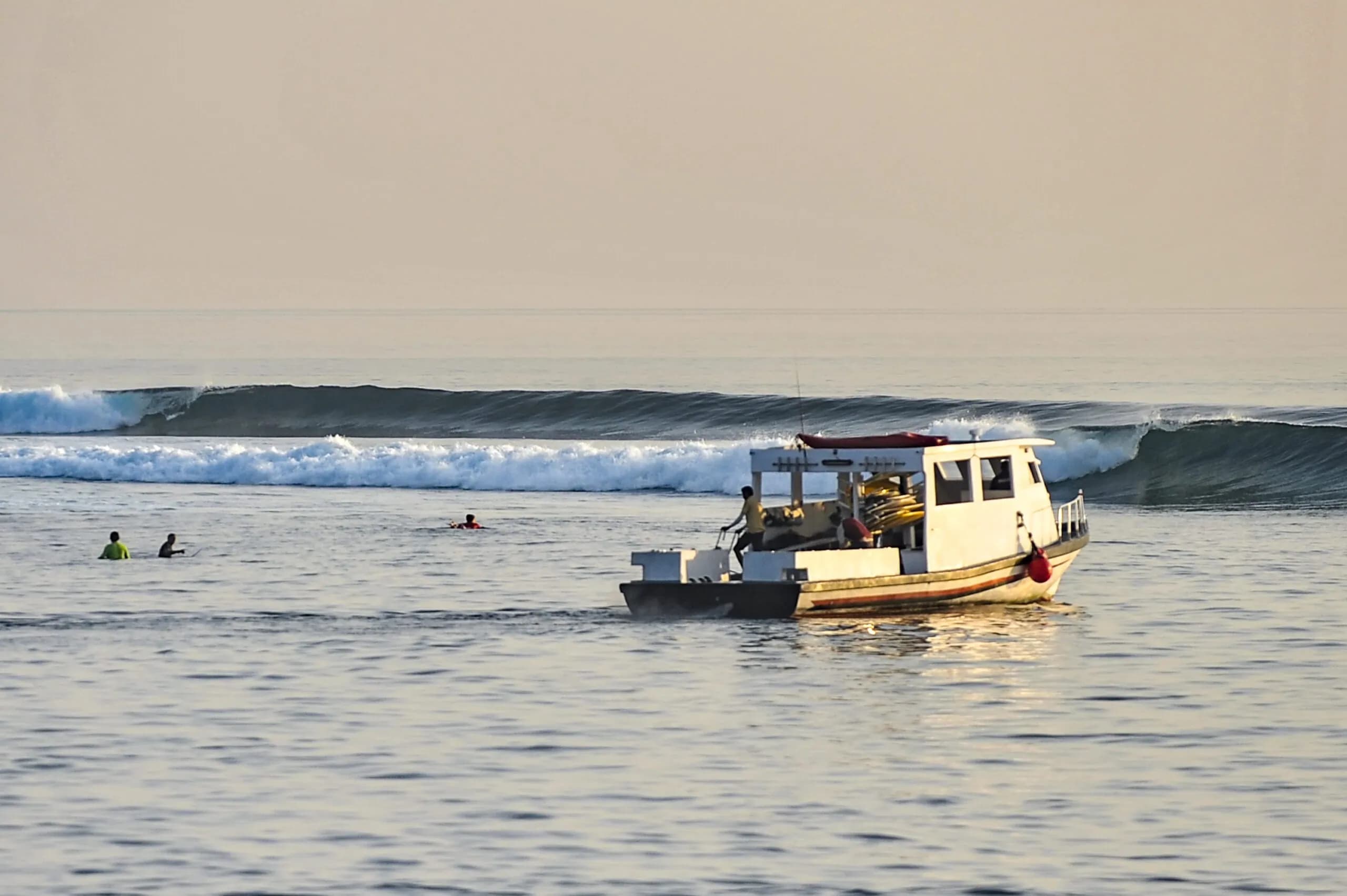 Traditional Maldivian dhoni boat at sunset near a left-hand surf break in the Maldives
