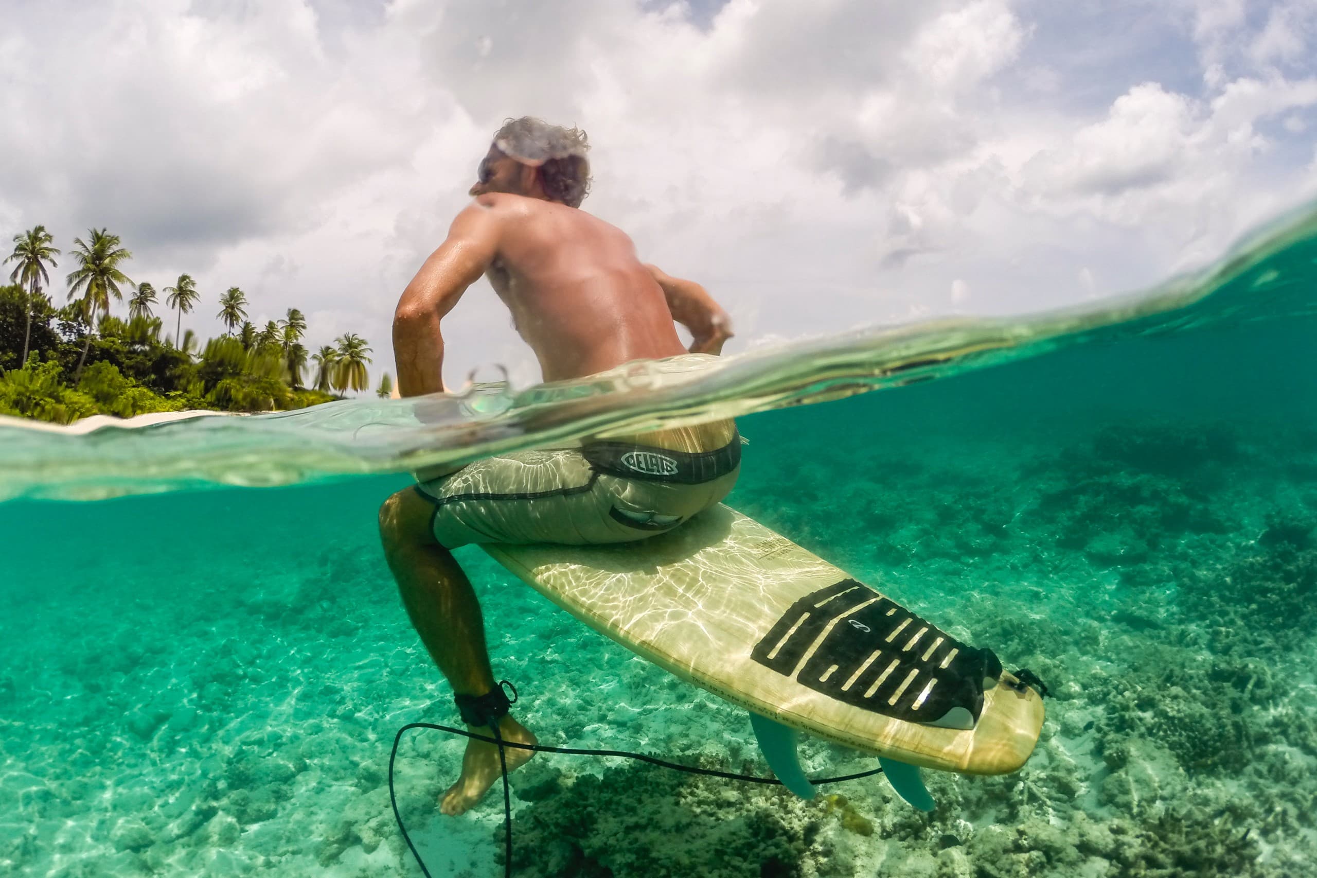 Surfers waiting in the lineup at a Maldives reef break with waves approaching