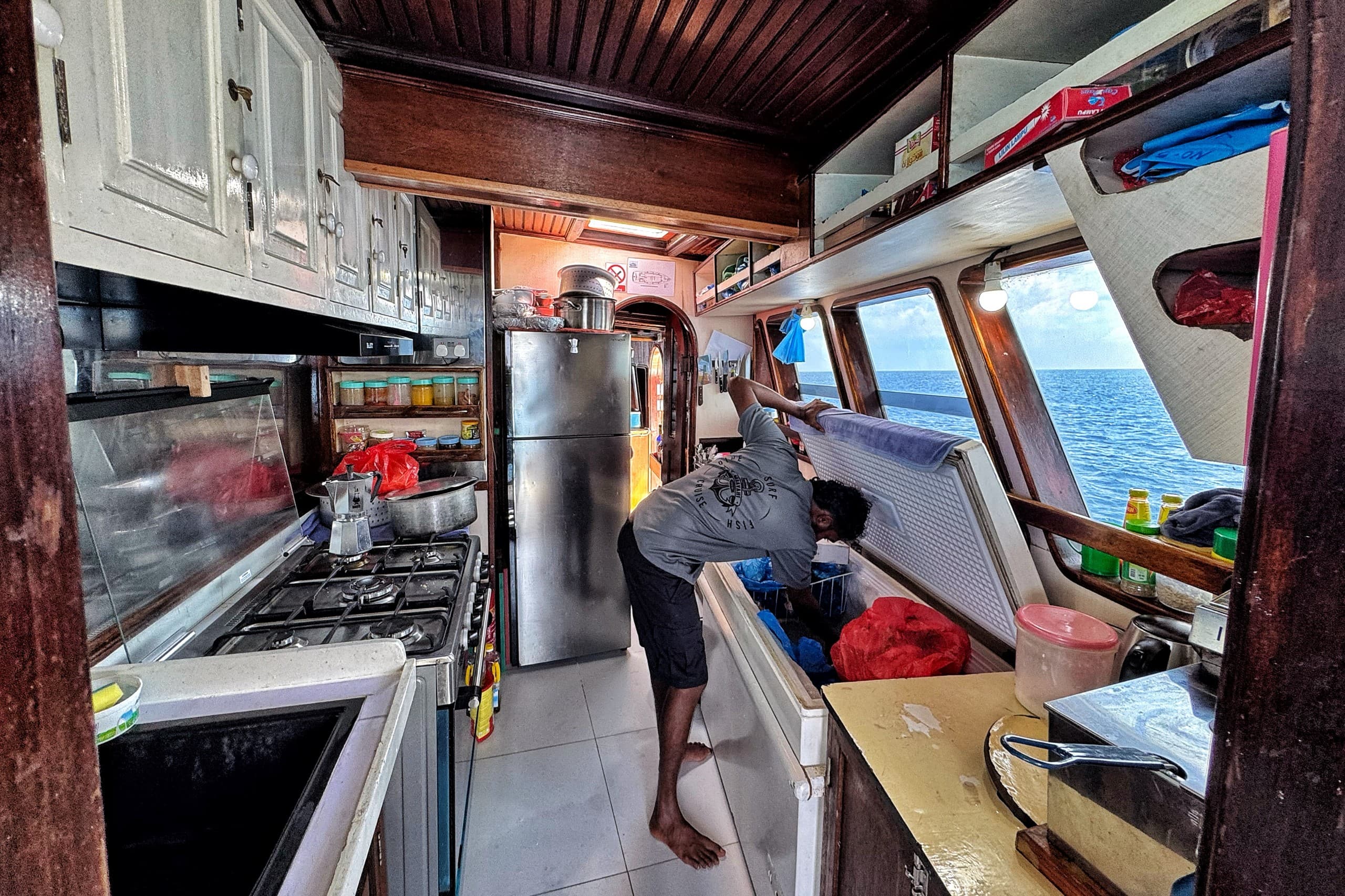 Crew preparing food in the kitchen on board Maavahi liveaboard in the Maldives