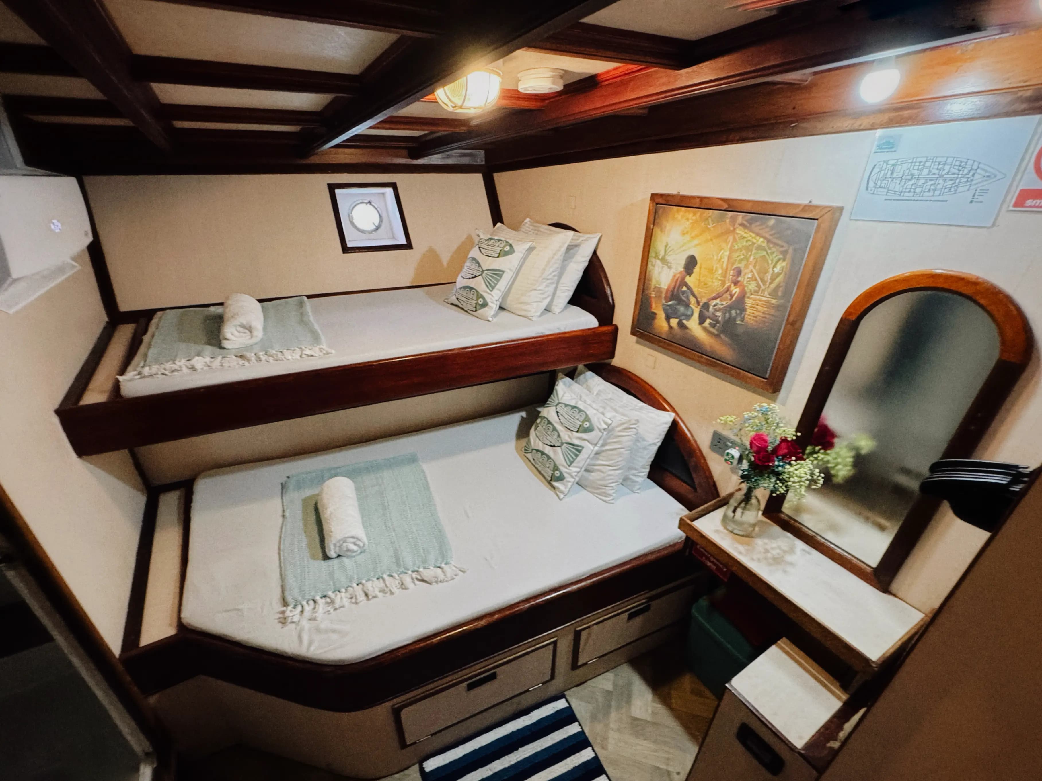 Close view of bunk beds inside Maavahi Maldives liveaboard cabin with pillows and linens