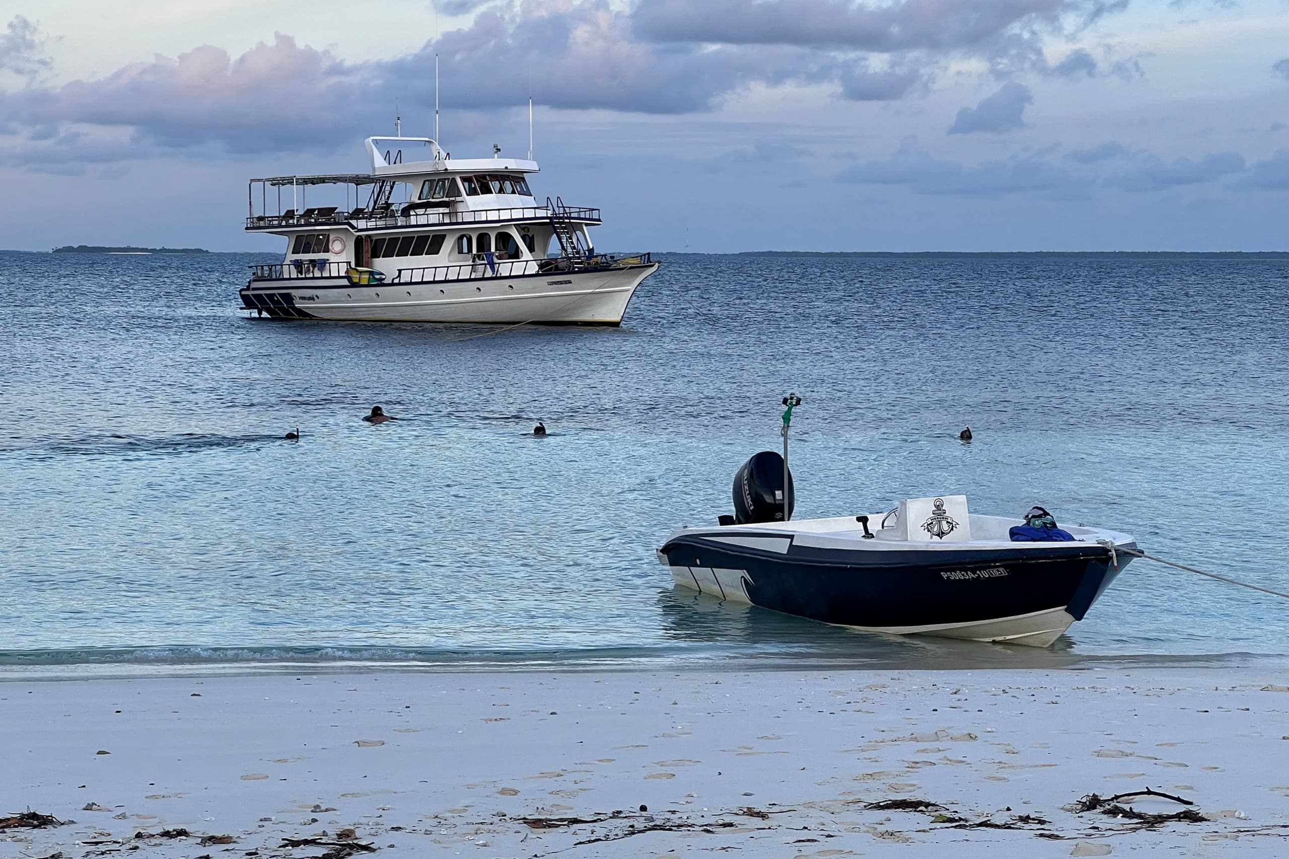 Dinghy tender on the beach with Maavahi liveaboard boat in the background in the Maldives