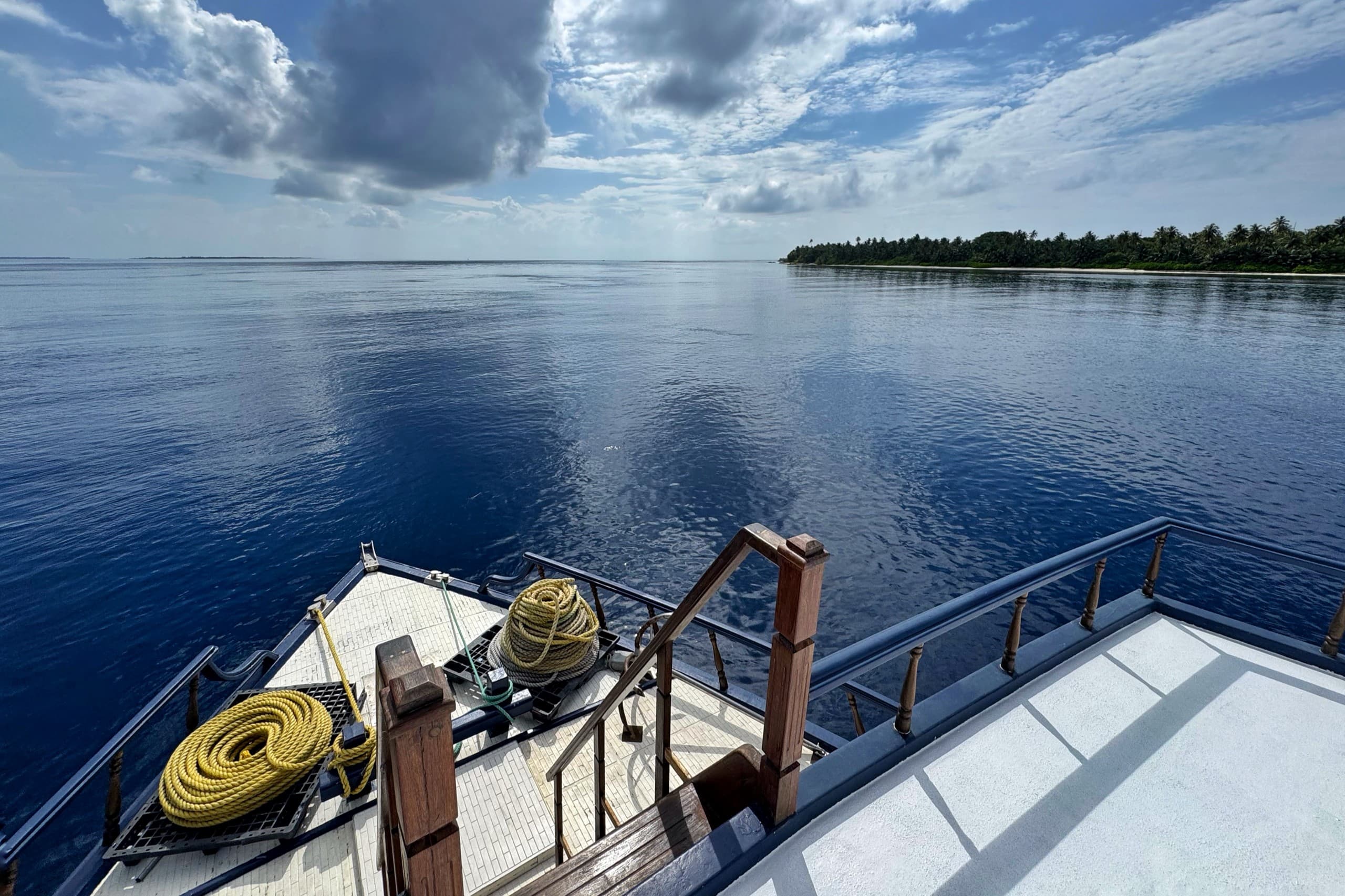 View from Maavahi liveaboard deck over the Maldives ocean with tropical island in the distance