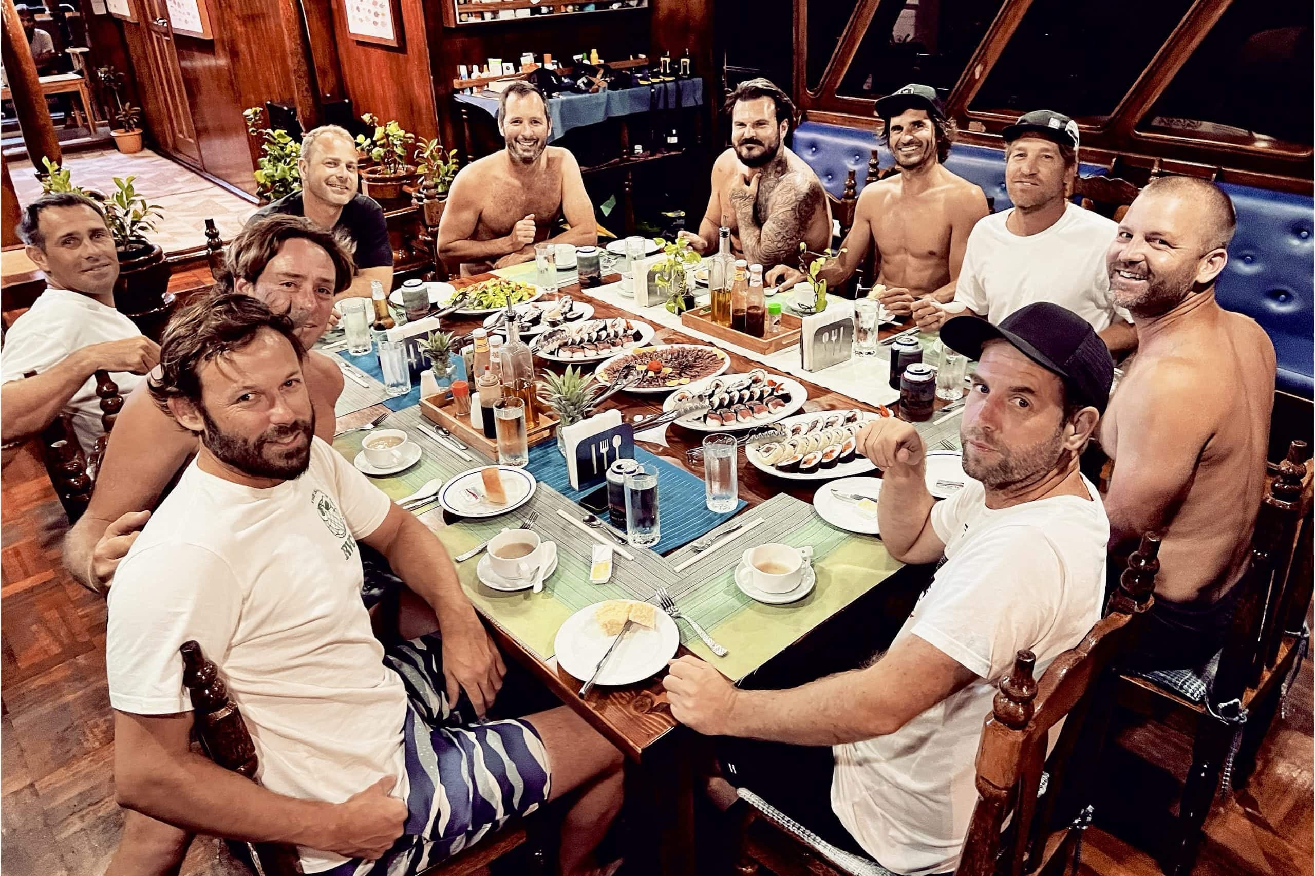 Group of surfers sharing dinner on board Maavahi during a Maldives liveaboard surf charter experience