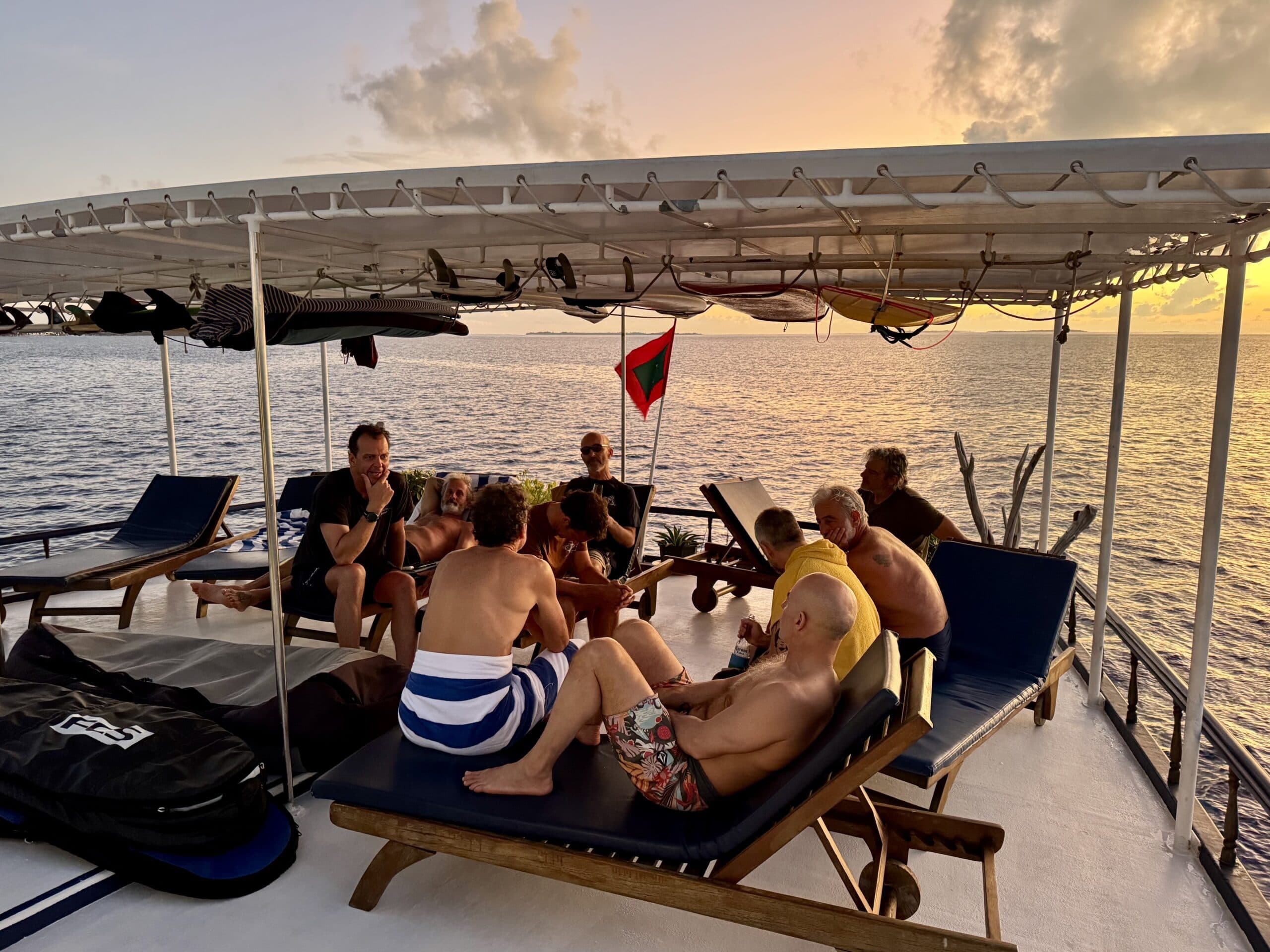 Group of guests enjoying sunset together on Maavahi Maldives liveaboard upper deck