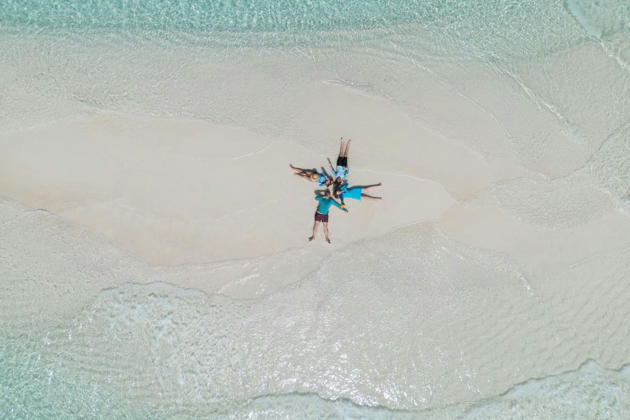 Group of friends relaxing together on a sandbank in the Maldives during a tropical island experience