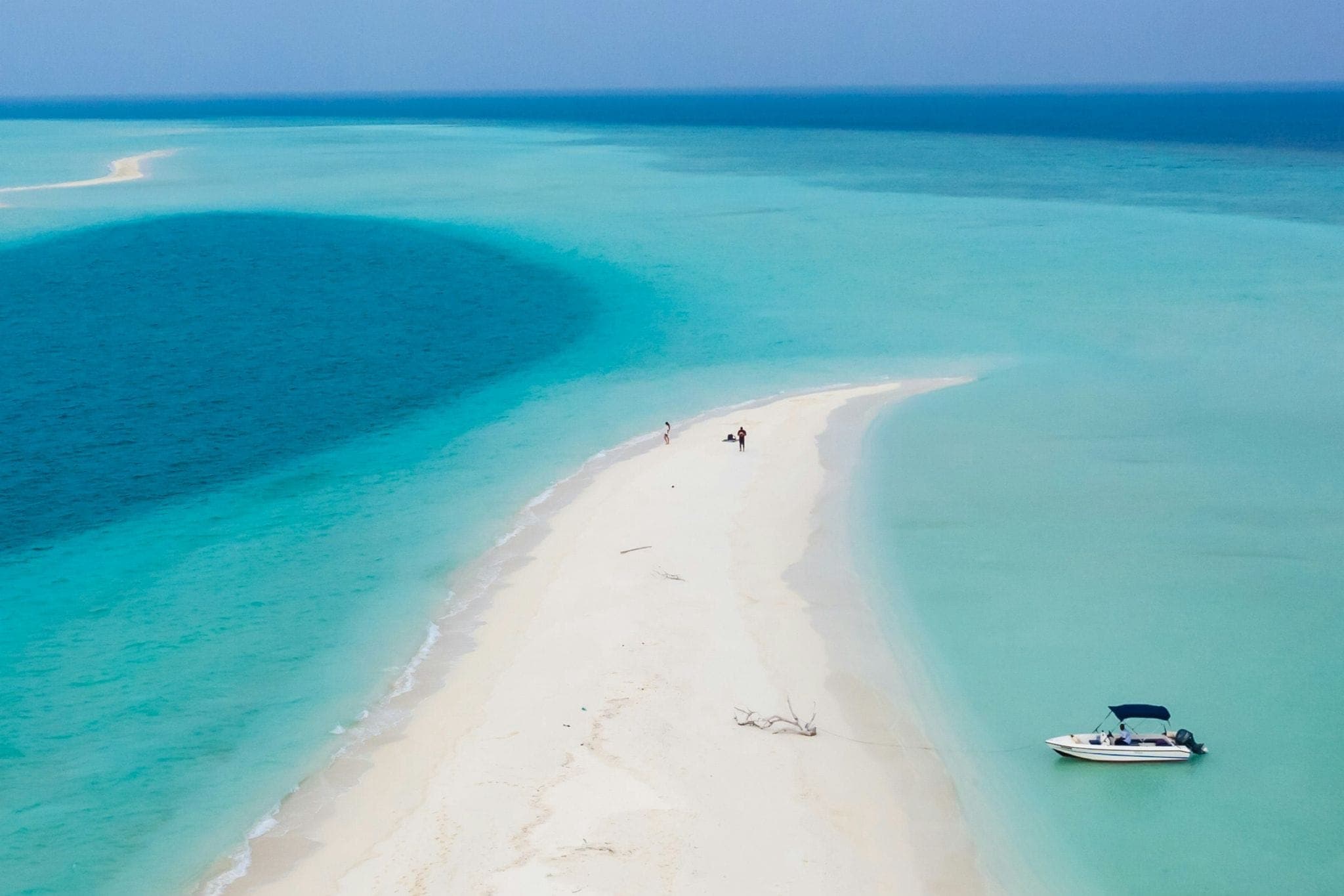 Couple enjoying a private sandbank in the Maldives with crystal clear water and boat nearby