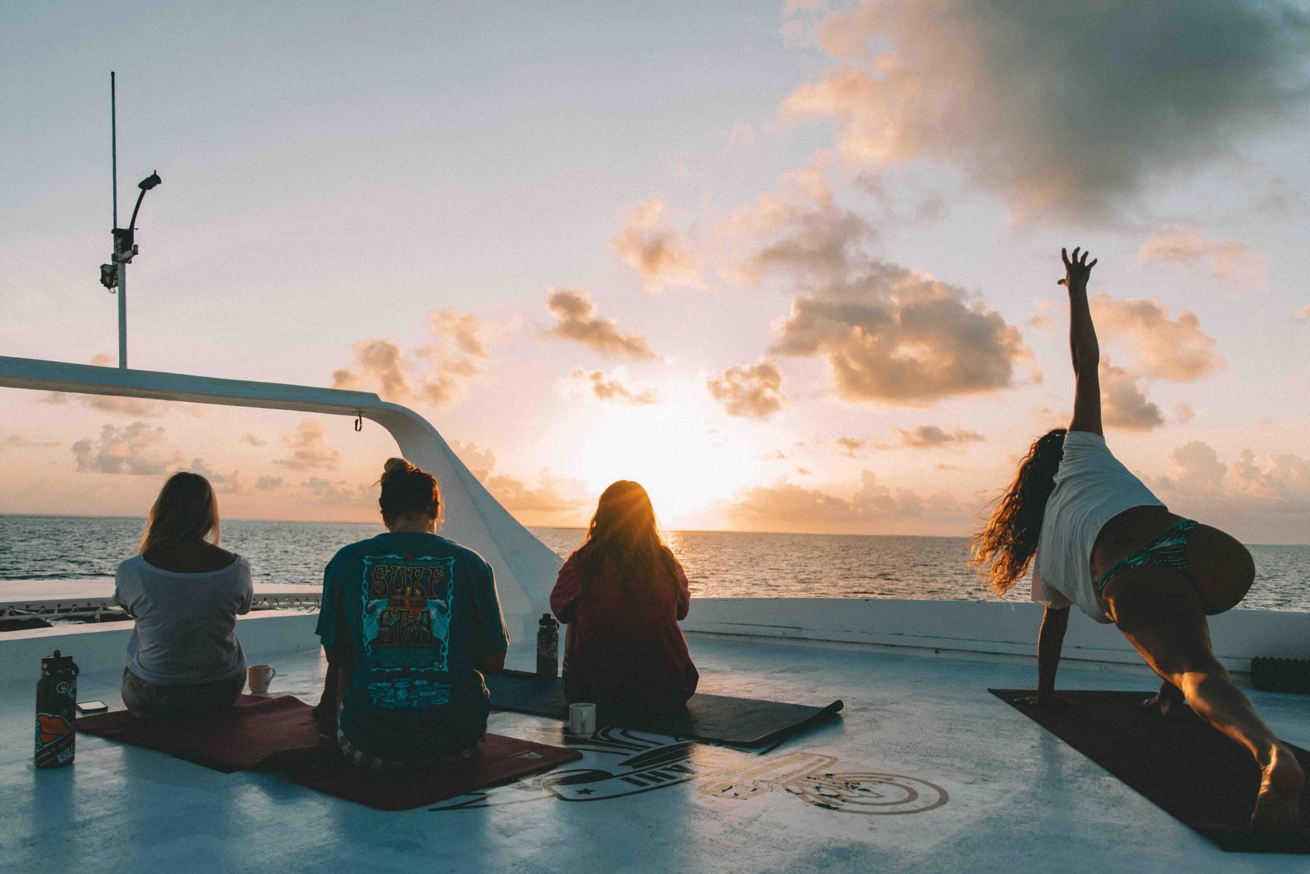 Group yoga session on a boat deck at sunset during a Maldives wellness retreat