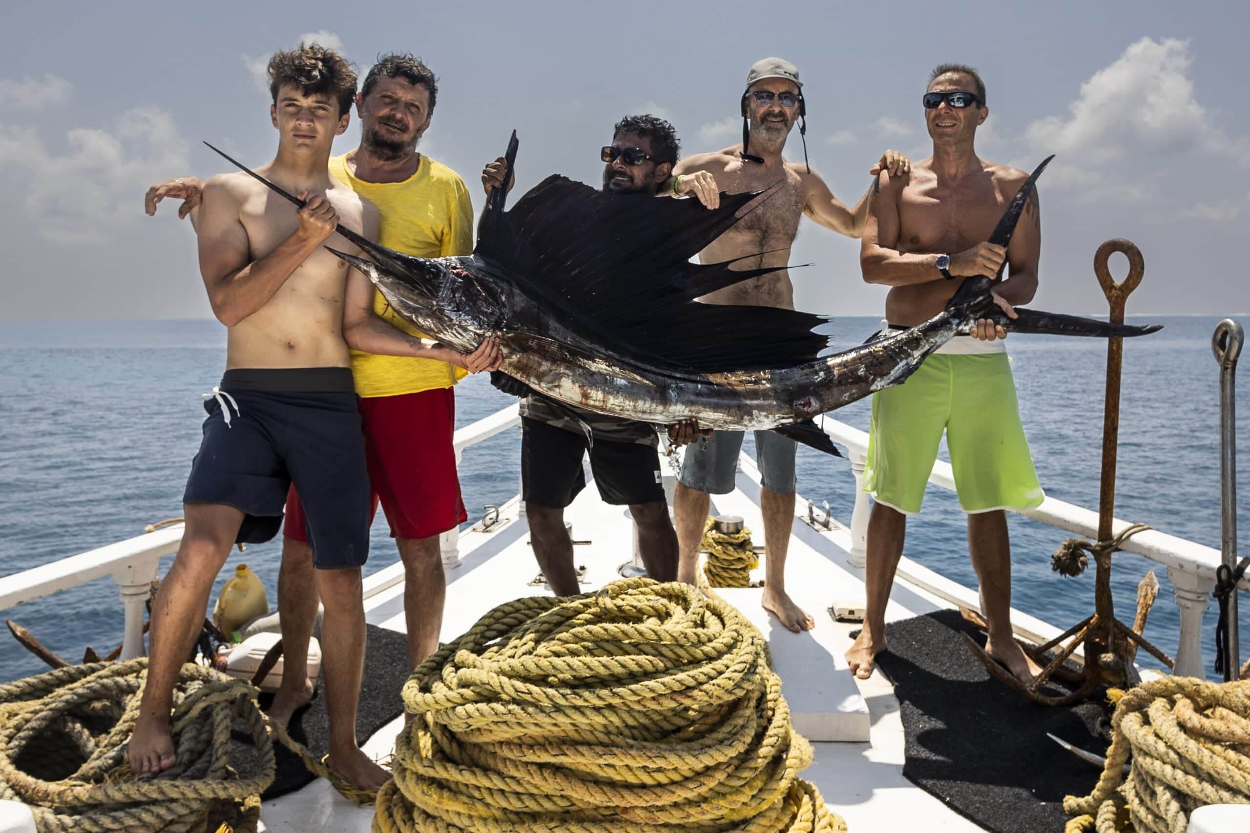 Big game fishing in Maldives with group holding a sailfish on boat in open ocean