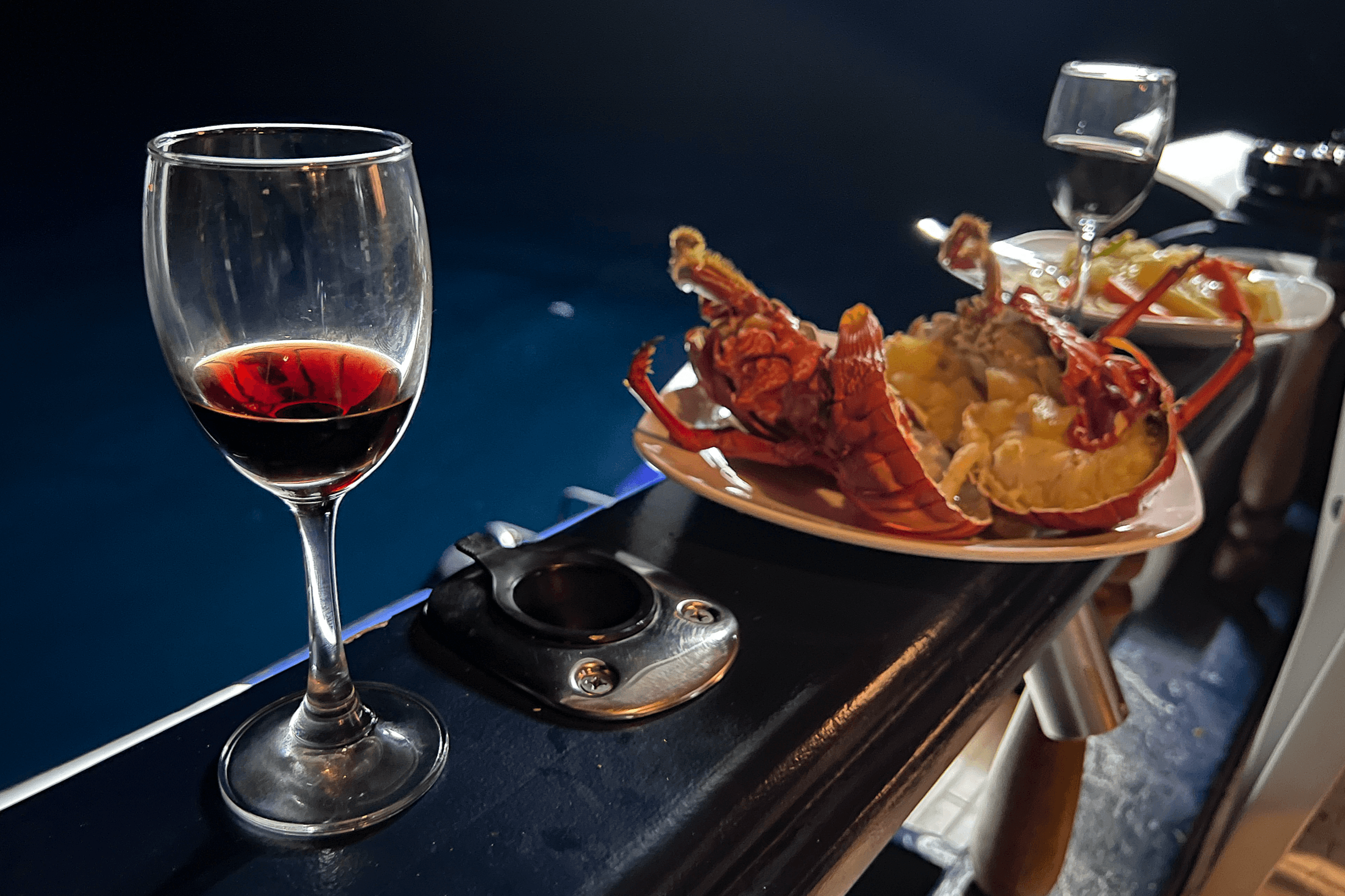 Fresh lobster dinner and red wine served on liveaboard boat in Maldives at sea