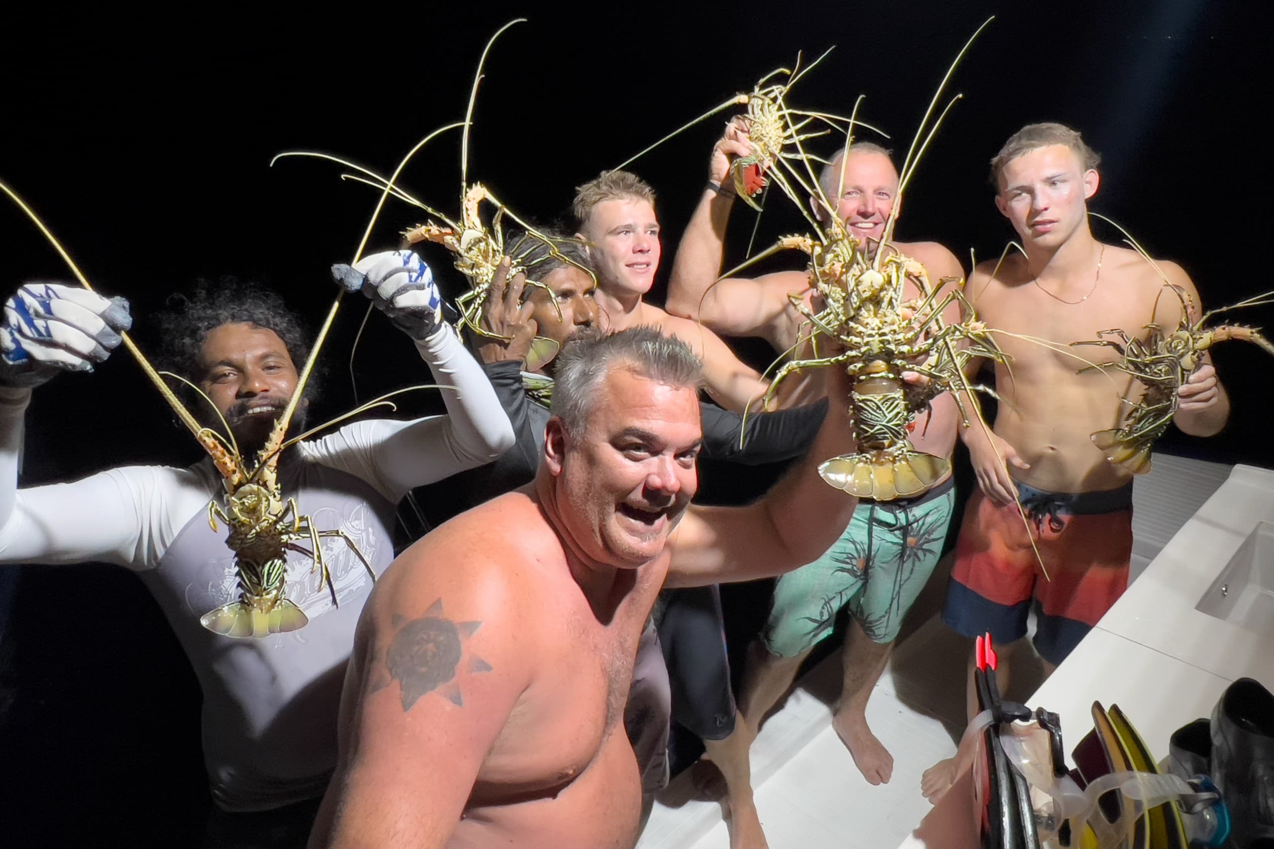 Night fishing in Maldives with Maavahi crew holding fresh lobsters on boat